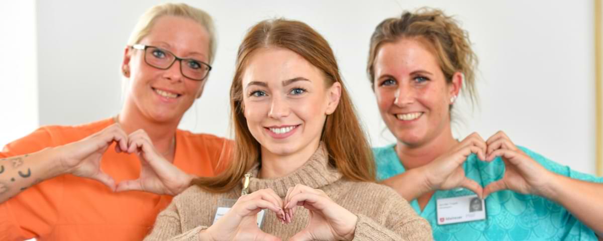 Altenpflegerinnen Herz Drei Altenpflegerinnen der Malteser formen ein Herz mit ihren Fingern.